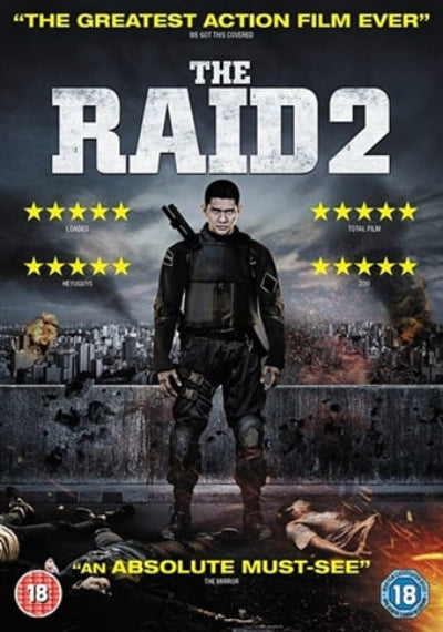 The movie poster for 'The Raid 2' featuring a central figure in tactical gear standing on a rooftop with a city skyline and explosions in the background. Large distressed white title text reads 'THE RAID 2' at the top, with yellow review stars and quotes around the figure.